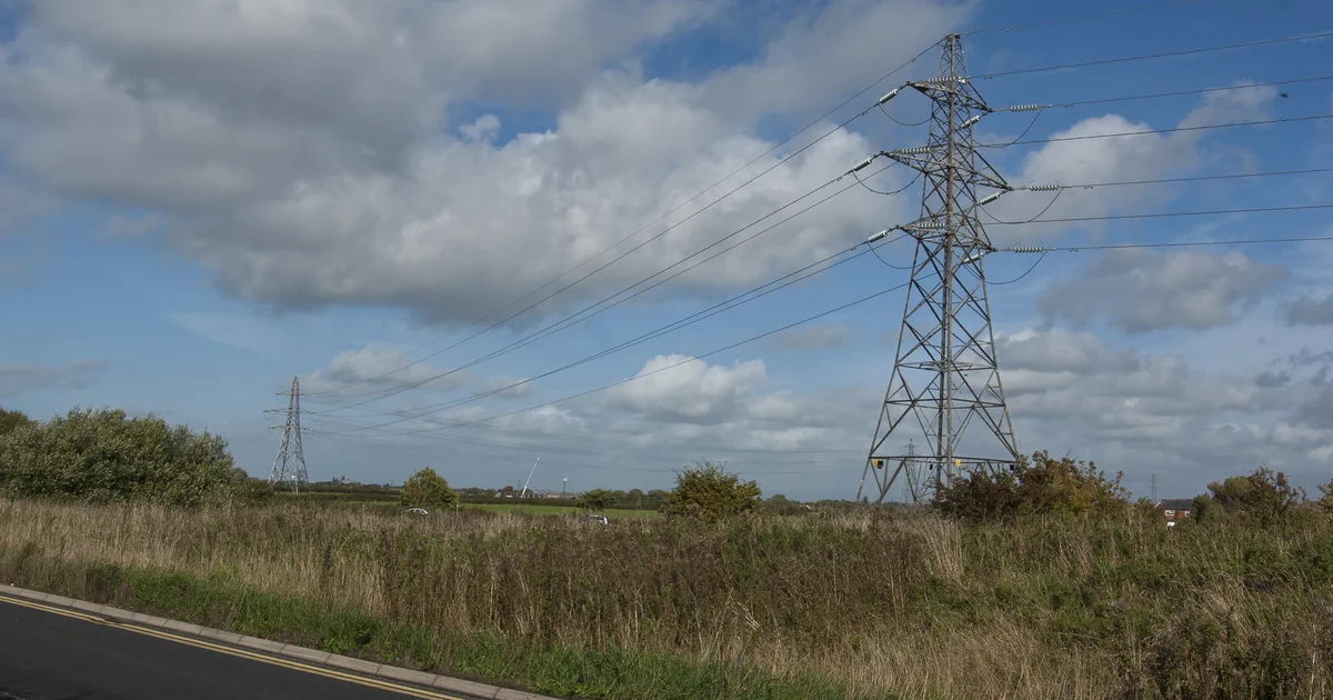 Electricity pylons crossing rough grassland near Thornton, Lancashire, close to the Hillhouse site.