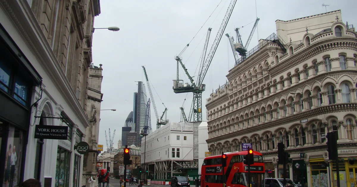 The Gherkin, the Cheese Grater and several construction cranes, seen from Queen Victoria Street in the City of London.