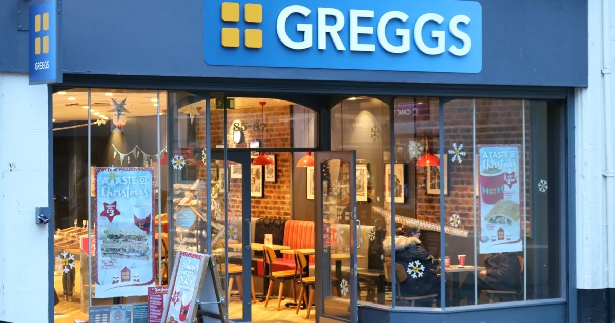 A Greggs shop on a high street, with the company's blue and white signage above the window.