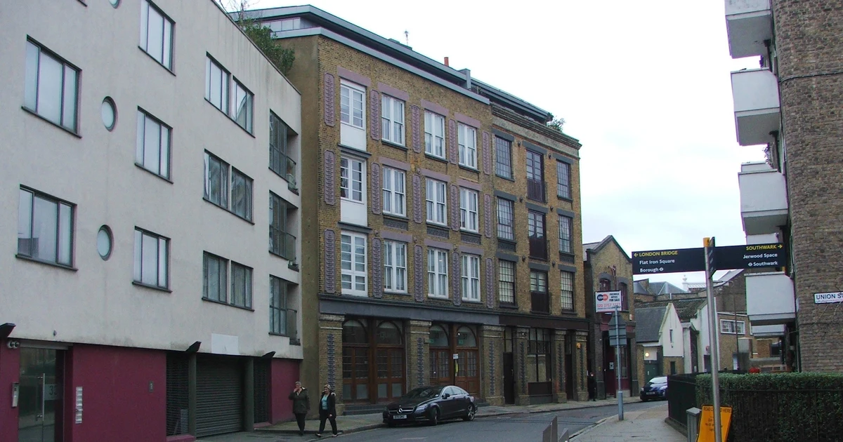 A converted industrial brick building on a street in Southwark, London, with a signpost pointing to London Bridge and Borough.
