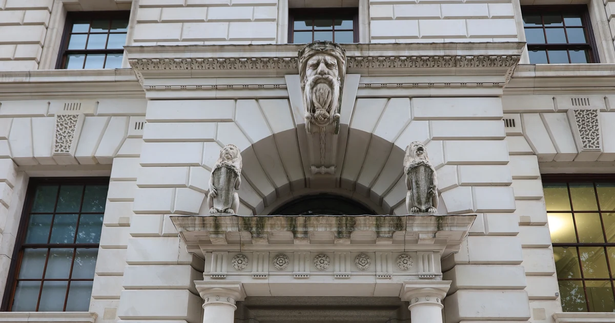 Carved stone keystone face and lion figures above the entrance porch of HM Treasury, 1 Horse Guards Road, London.