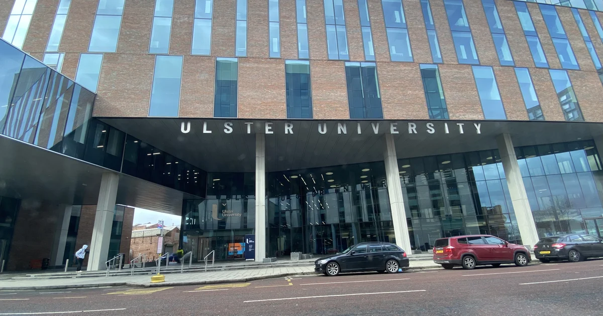 The entrance to Ulster University's Belfast campus building, with the university's name in large lettering above the doors.